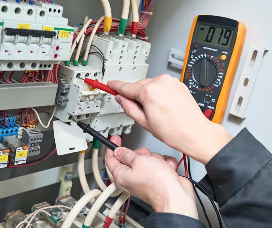 Eléctrico realizando mediciones eléctricas en un panel de control