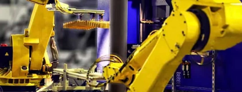 Sistema de automatización robótica, con dos brazos robóticos industriales de color amarillo en un entorno de fábrica