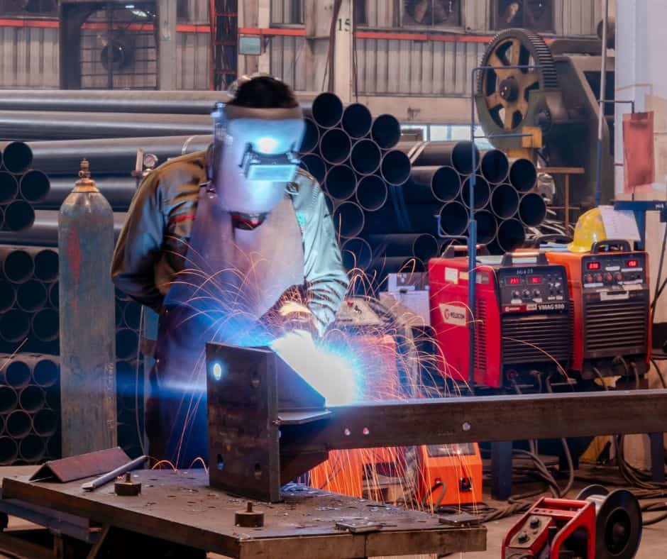 Soldador en una fábrica, realizando trabajos de soldadura en una estructura metálica.